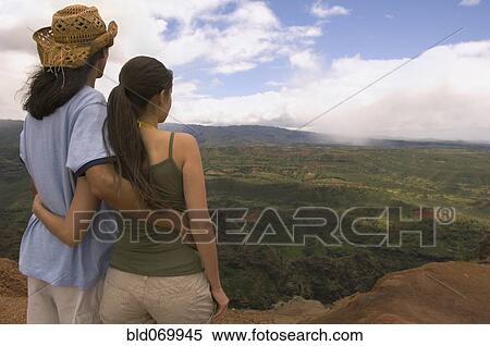 Stock Photography - Couple hugging and looking out over landscape. Fotosearch
