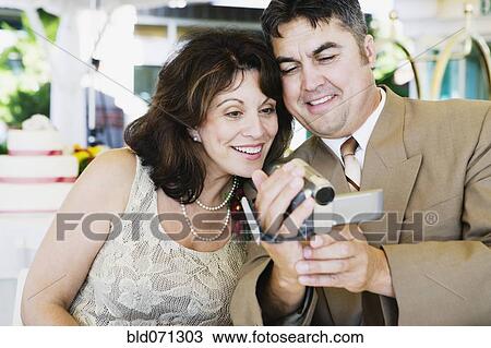 Couple looking at video recorder at wedding View Large Photo Image Stock Image - Couple looking at video recorder at wedding. Fotosearch