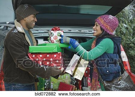 Couple unloading Christmas presents from car trunk View Large Photo Image Stock Image - Couple unloading Christmas presents from car trunk. Fotosearch