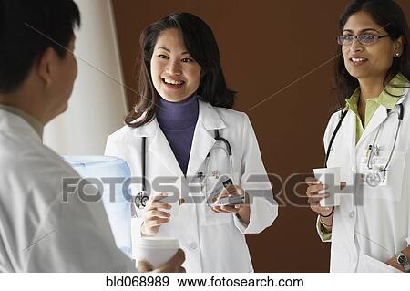 Doctors talking around water cooler View Large Photo Image Stock Photo - Doctors talking around water cooler. Fotosearch
