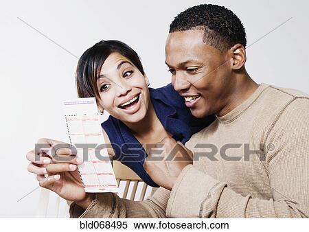 Stock Photography - Excited couple looking at lottery ticket. Fotosearch