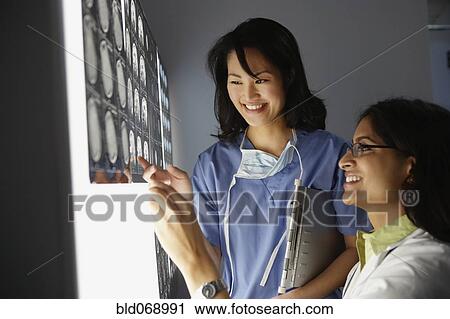 Stock Image - Female doctors looking at x-rays. Fotosearch