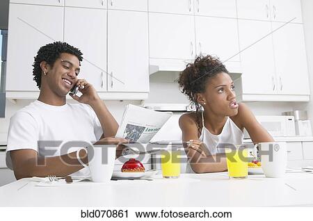 Stock Image - Frustrated African woman in kitchen with boyfriend. Fotosearch