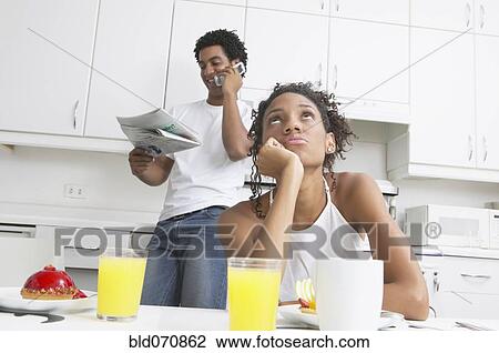 Stock Image - Frustrated African woman in kitchen with boyfriend. Fotosearch