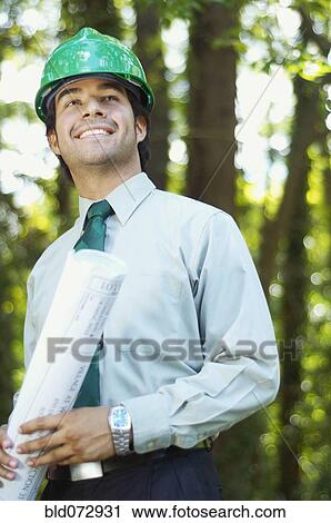 Hispanic architect holding blueprint and wearing green hard hat View Large Photo Image Stock Image - Hispanic architect holding blueprint and wearing green hard hat. Fotosearch