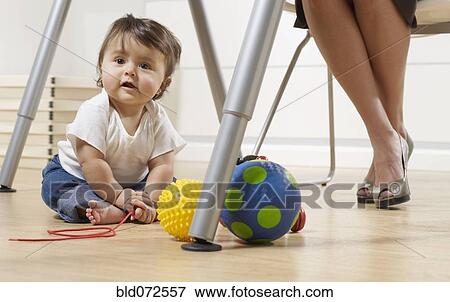 Hispanic baby boy sitting under mother's desk in home office View Large Photo Image Stock Photo - Hispanic baby boy sitting under mother's desk in home office. Fotosearch