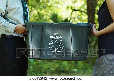 Stock Image - Hispanic business people carrying recycling bin. Fotosearch