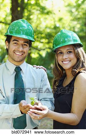 Hispanic business people with green hard hats holding tree sprout View Large Photo Image Stock Image - Hispanic business people with green hard hats holding tree sprout. Fotosearch