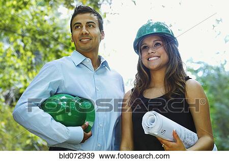 Stock Photo - Hispanic business people with green hard hats. Fotosearch