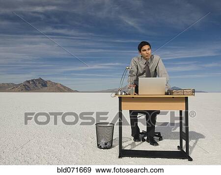 Stock Photo - Hispanic businessman at desk on salt flats. Fotosearch
