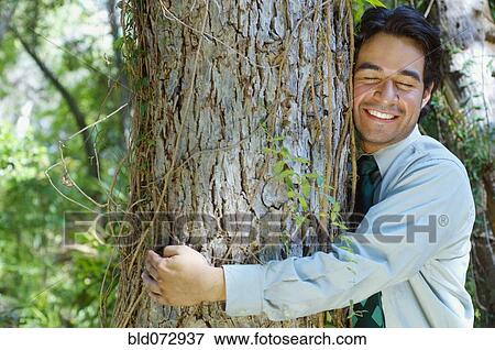 Stock Photo - Hispanic businessman hugging tree. Fotosearch