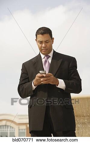 Hispanic businessman looking at cell phone View Large Photo Image Stock Image - Hispanic businessman looking at cell phone. Fotosearch