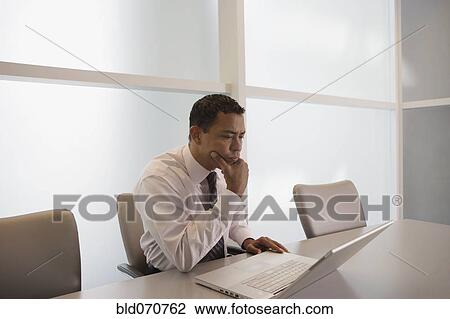 Stock Image - Hispanic businessman looking at laptop. Fotosearch