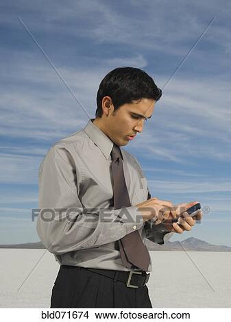 Picture - Hispanic businessman looking at electronic organizer. Fotosearch