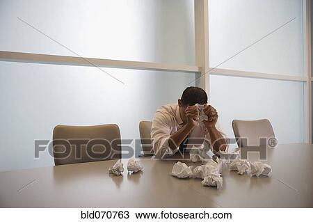 Stock Image - Hispanic businessman next to pile of crumpled paper. Fotosearch