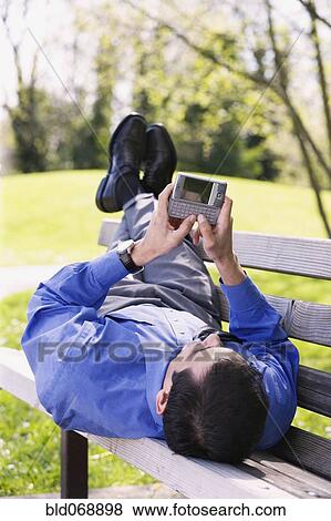 Stock Photo - Hispanic businessman using PDA outdoors. Fotosearch