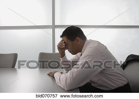 Stock Photo - Hispanic businessman with head in hand. Fotosearch