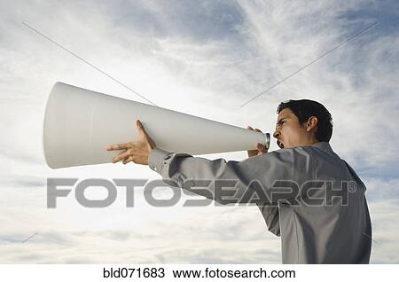 Stock Image - Hispanic businessman yelling into megaphone. Fotosearch