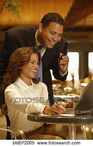 Stock Photography - Hispanic businesspeople looking at laptop. Fotosearch
