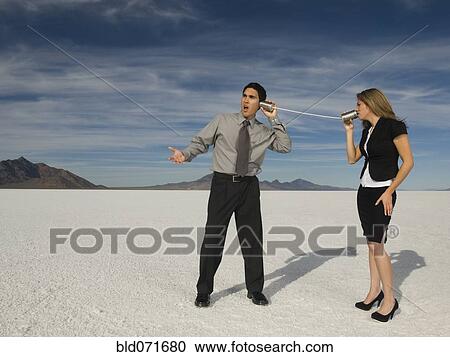 Stock Image - Hispanic businesspeople talking on can and string telephone. Fotosearch