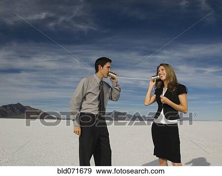 Stock Photo - Hispanic businesspeople talking on can and string telephone. Fotosearch