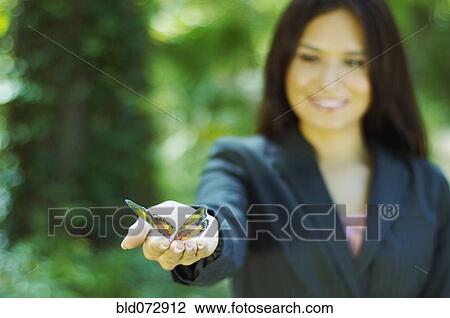 Stock Image - Hispanic businesswoman holding butterfly. Fotosearch