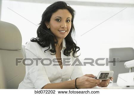 Stock Image - Hispanic businesswoman holding cell phone. Fotosearch