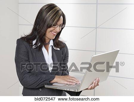 Hispanic businesswoman holding laptop View Large Photo Image Stock Photo - Hispanic businesswoman holding laptop. Fotosearch