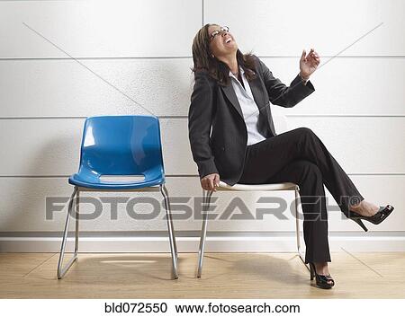 Stock Image - Hispanic businesswoman laughing in waiting room. Fotosearch