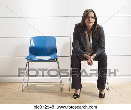 Stock Photo - Hispanic businesswoman sitting in waiting room. Fotosearch