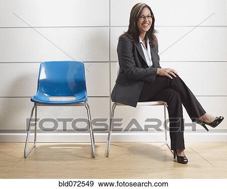 Stock Photo - Hispanic businesswoman sitting in waiting room. Fotosearch