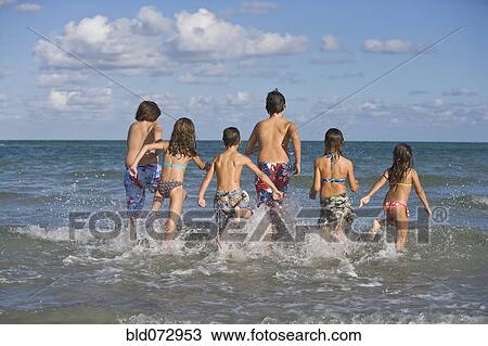 Hispanic children running through ocean surf View Large Photo Image Stock Image - Hispanic children running through ocean surf. Fotosearch