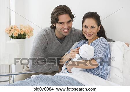 Hispanic couple holding newborn baby in hospital bed View Large Photo Image Picture - Hispanic couple holding newborn baby in hospital bed. Fotosearch