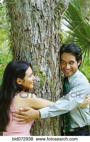 Hispanic couple hugging tree View Large Photo Image Stock Photo - Hispanic couple hugging tree. Fotosearch