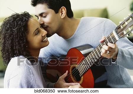 Stock Image - Hispanic couple with guitar kissing. Fotosearch