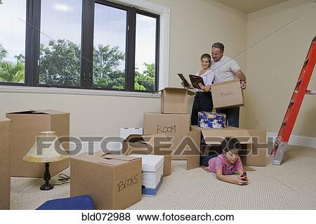 Stock Photo - Hispanic family in living room with cardboard boxes. Fotosearch
