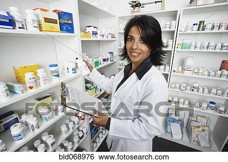 Stock Photograph - Hispanic female pharmacist shelving medication. Fotosearch