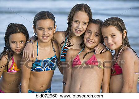 Stock Image - Hispanic girls in bikinis posing on beach. Fotosearch