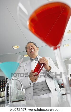 Stock Photo - Hispanic host mixing martini cocktails at party. Fotosearch