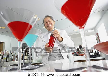 Stock Photograph - Hispanic host mixing martini cocktails at party. Fotosearch