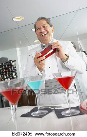 Stock Photography - Hispanic host mixing martini cocktails at party. Fotosearch