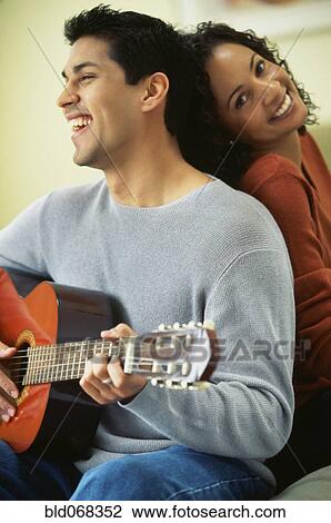 Stock Image - Hispanic man playing guitar for girlfriend. Fotosearch