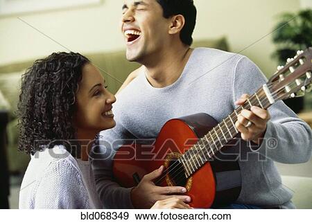 Stock Photo - Hispanic man playing guitar for girlfriend. Fotosearch
