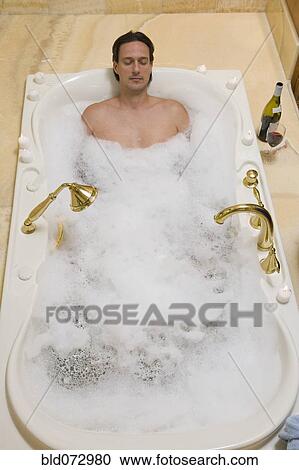 Stock Image - Hispanic man relaxing in bubble bath. Fotosearch