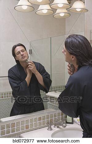 Hispanic man shaving in bathroom mirror View Large Photo Image Stock Photo - Hispanic man shaving in bathroom mirror. Fotosearch