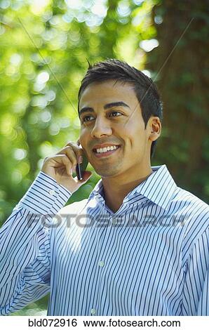 Hispanic man talking on cell phone outdoors View Large Photo Image Stock Photograph - Hispanic man talking on cell phone outdoors. Fotosearch