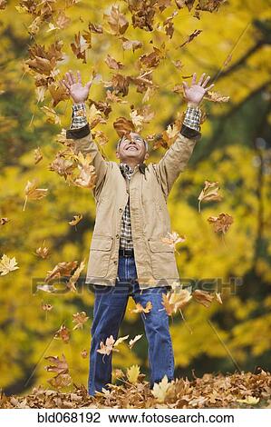 Stock Image - Hispanic man throwing autumn leaves. Fotosearch