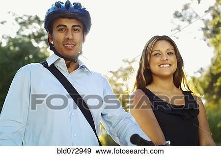 Stock Photo - Hispanic man wearing bike helmet posing with girlfriend. Fotosearch
