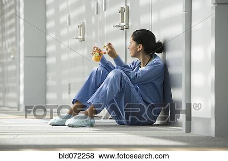 Hispanic nurse eating fruit on floor View Large Photo Image Stock Photo - Hispanic nurse eating fruit on floor. Fotosearch