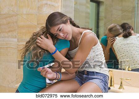 Stock Photography - Hispanic teenager crying and holding pregnancy test in bathroom. Fotosearch